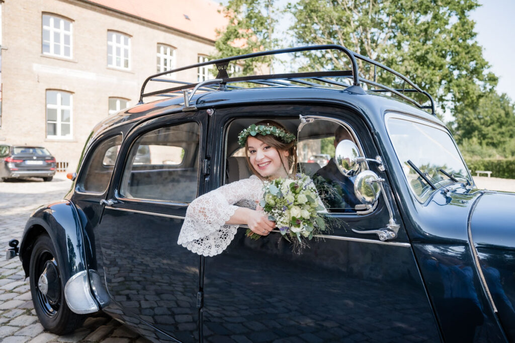 Braut schaut aus einem alten Auto