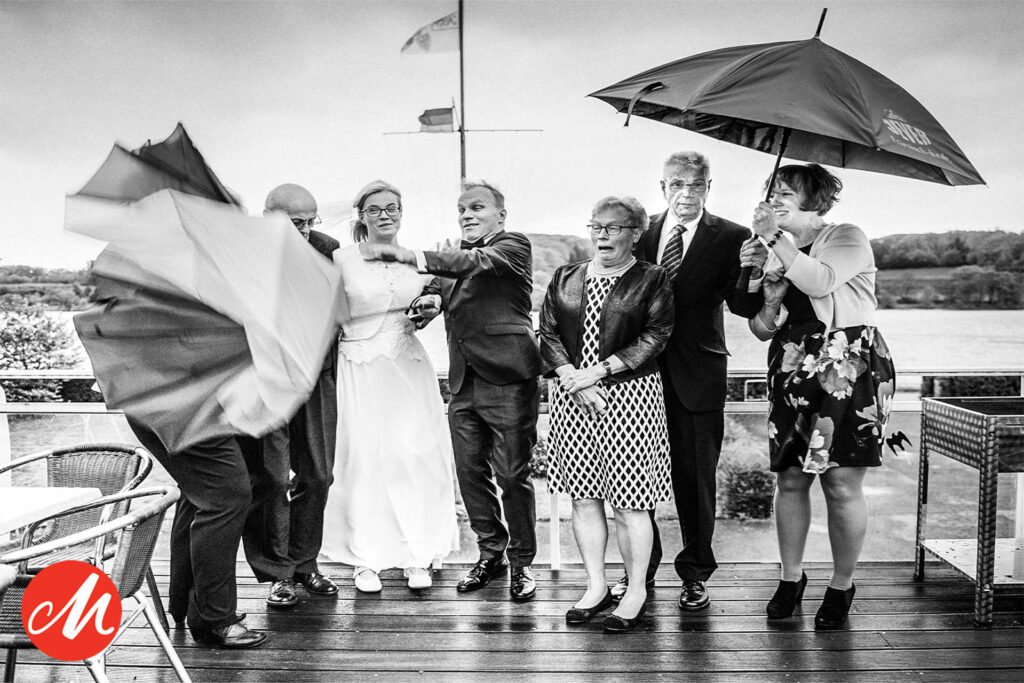 Hochzeitsfotograf Essen fotografiert eine Hochzeitsgesellschaft mit Regenschirmen am Wasser