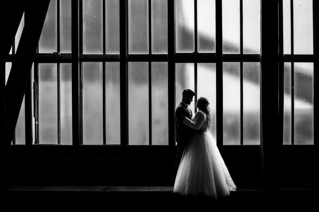Hochzeitsfotograf Essen fotografiert ein Brautpaar vor den Fenstern auf Zeche Zollverein