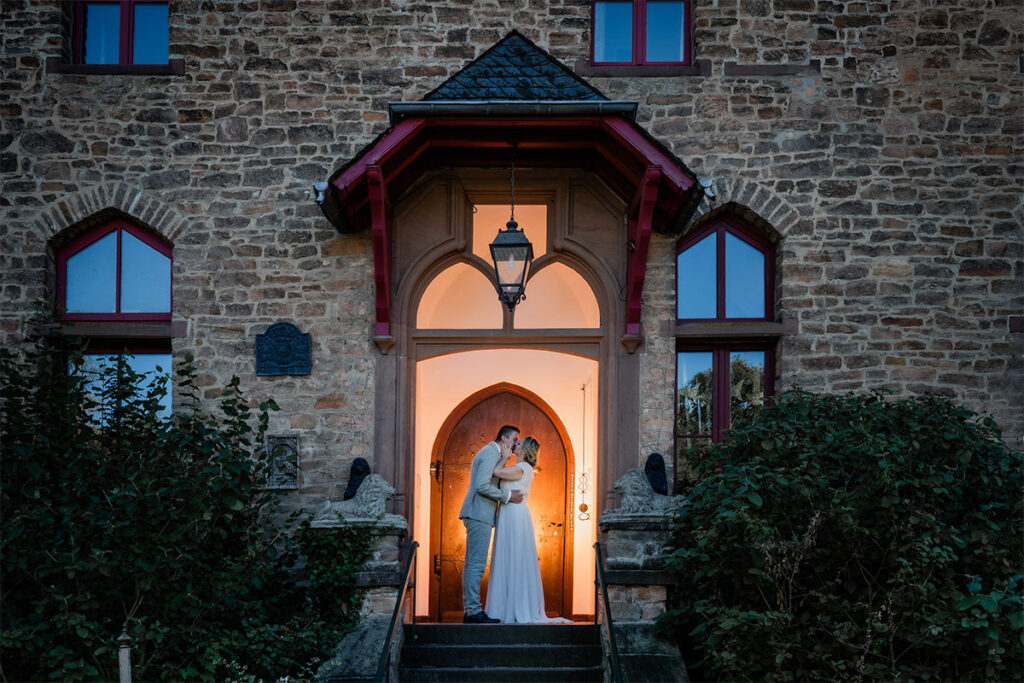 Brautpaar auf Burg Satzvey flirtet vor dem Eingang