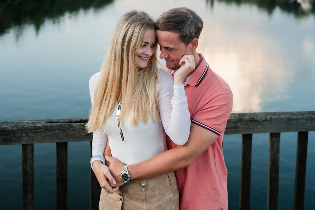 junges Paar steht auf einer Brücke über dem Wasser und flirtet