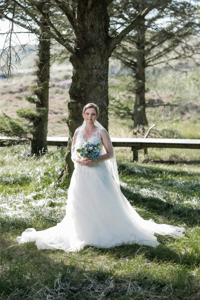 Hochzeitsfotograf Essen fotografiert die Braut mit Hochzeitsstrauß im Wald mit Bäumen