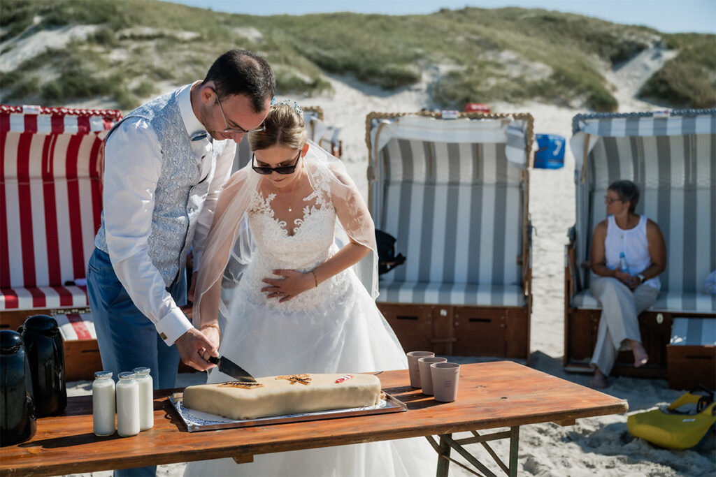 Hochzeitsfotograf Essen fotografiert den Anschnitt der Hochzeitstorte am Strand