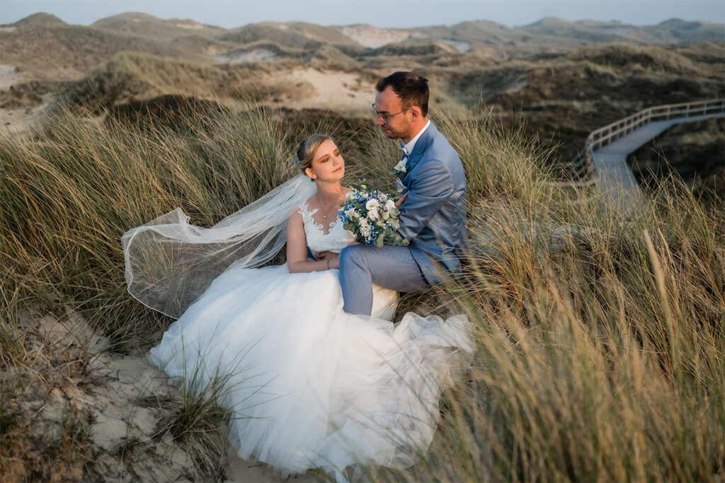 Brautpaar sitzt in den Dünen von Amrum in der Natur