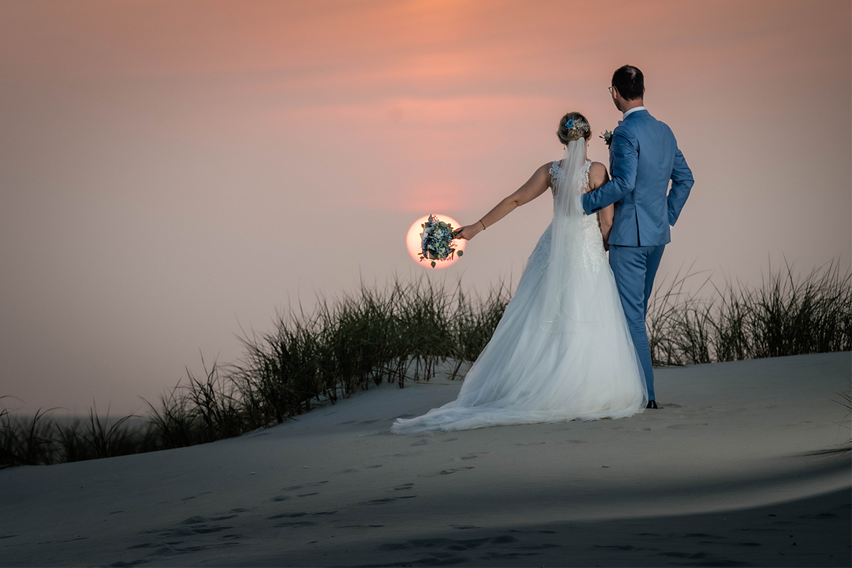 Brautpaar schaut sich den Sonnenuntergang nach der Hochzeitfeier auf Amrum
