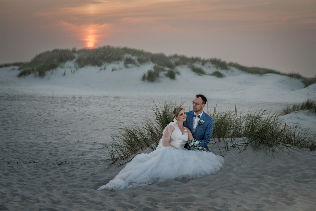 Brautpaar sitzt am Strand von Amrum im Sonnenuntergang