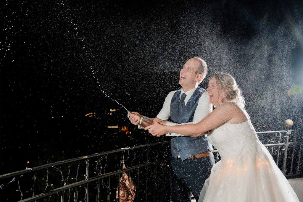 Hochzeitsfotograf Essen fotografiert ein Brautpaar das eine Flasche Sekt öffnet