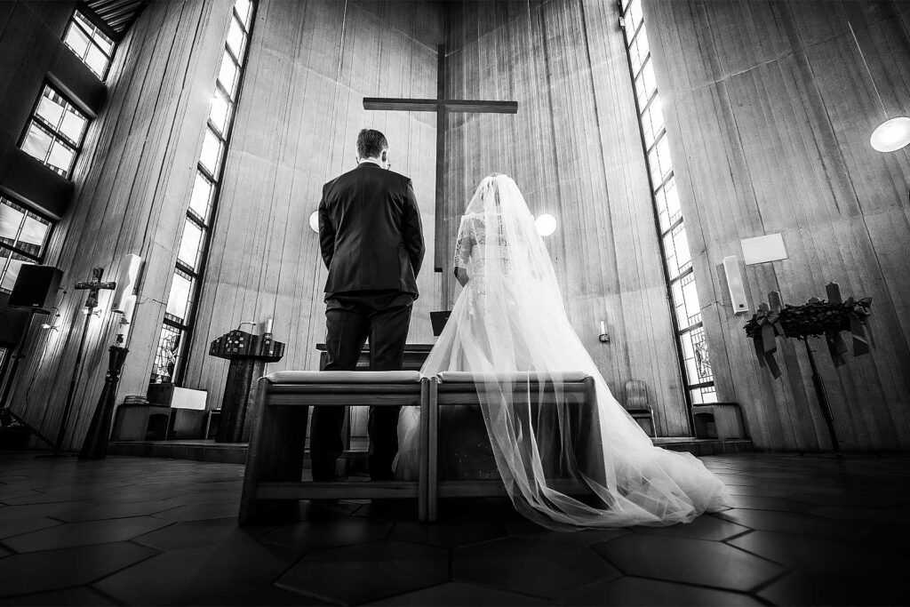 Brautpaar steht in der Kirche und empfängt den Segen