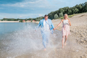 Brautpaar rennt durch das Wasser und freut sich