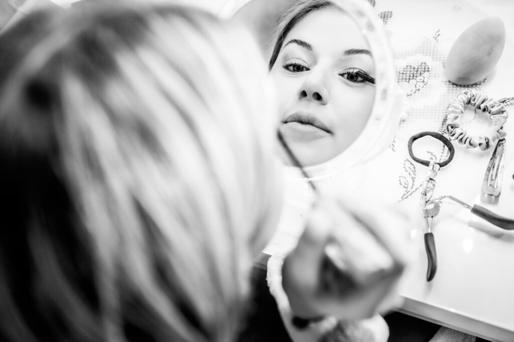 junge Frau schminkt sich im Spiegel