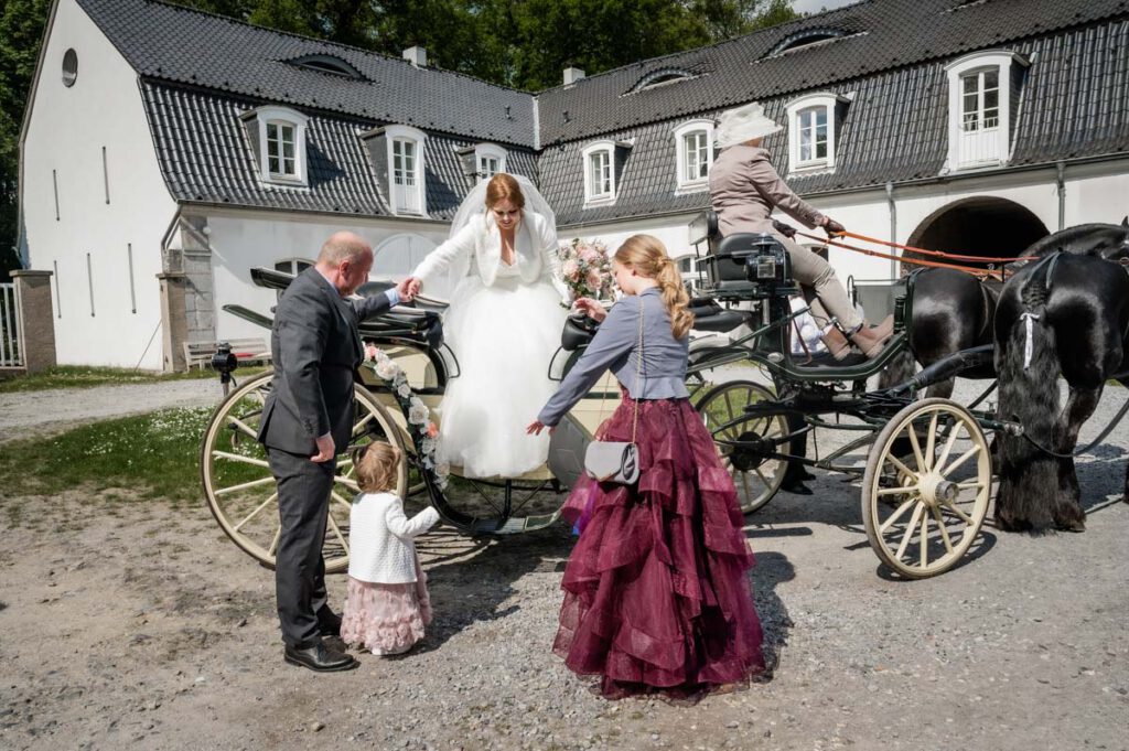 Braut steigt in den Händen ihres Vaters von der Hochzeitskutsche
