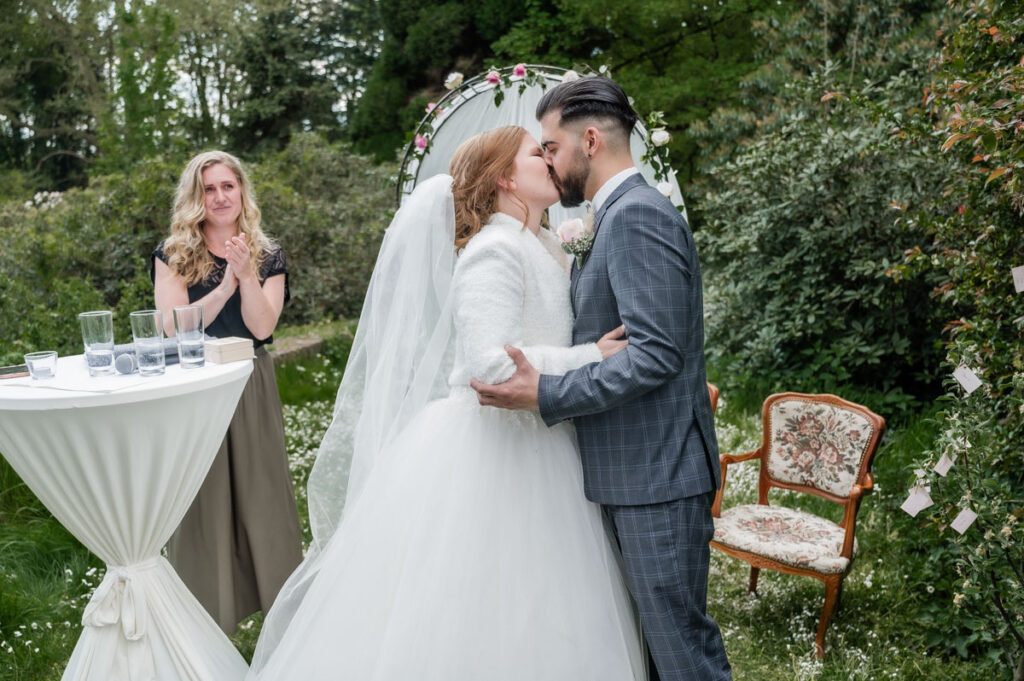Hochzeitsfotograf Essen fotografiert das küssende Brautpaar mit Traurednerin