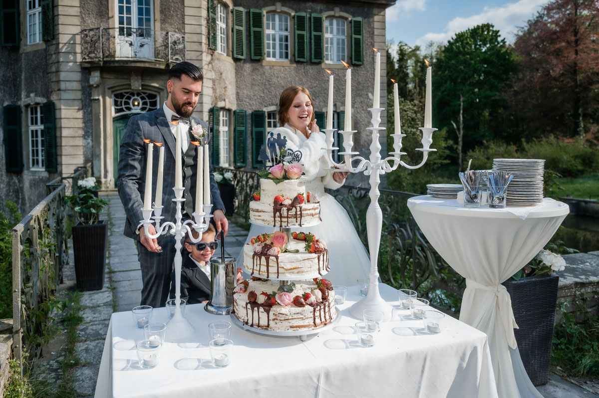 Hochzeitsfotograf Essen fotografiert das sich freuende Brautpaar über die Hochzeitstorte