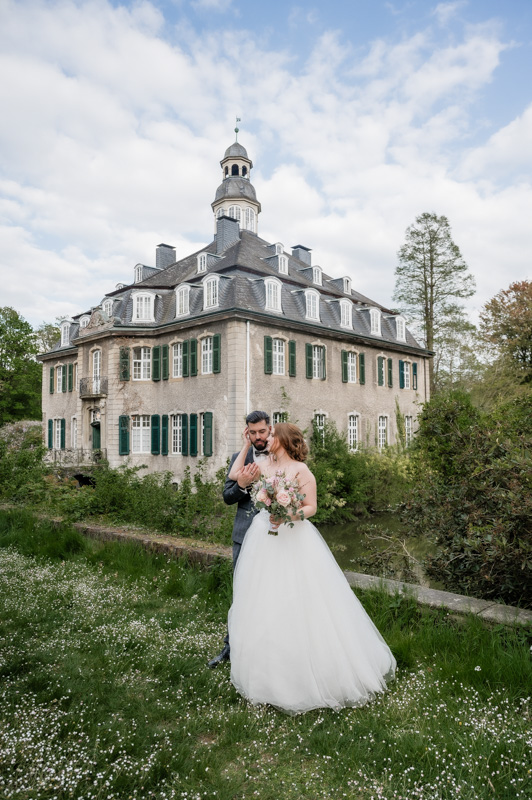 Hochzeitsfotograf Essen fotografiert ein junges Brautpaar vor dem Wasserschloss Hackhausen