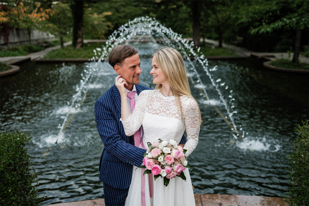 junges Brautpaar flirtet am Springbrunnen am Hochzeitstag