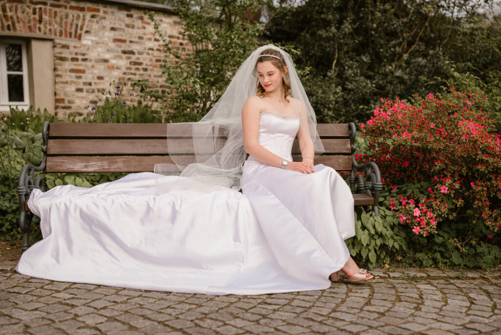Braut sitzt auf der Bank mit einem schönen Brautkleid