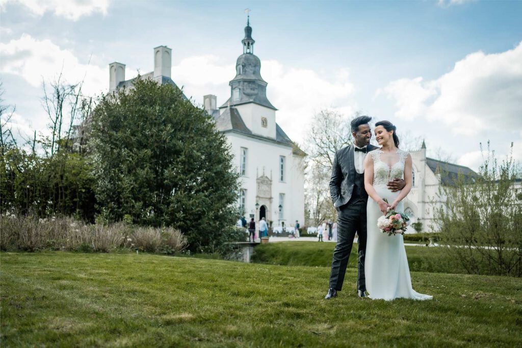 Brautpaar steht auf dem Rasen von Schloss Gartrop