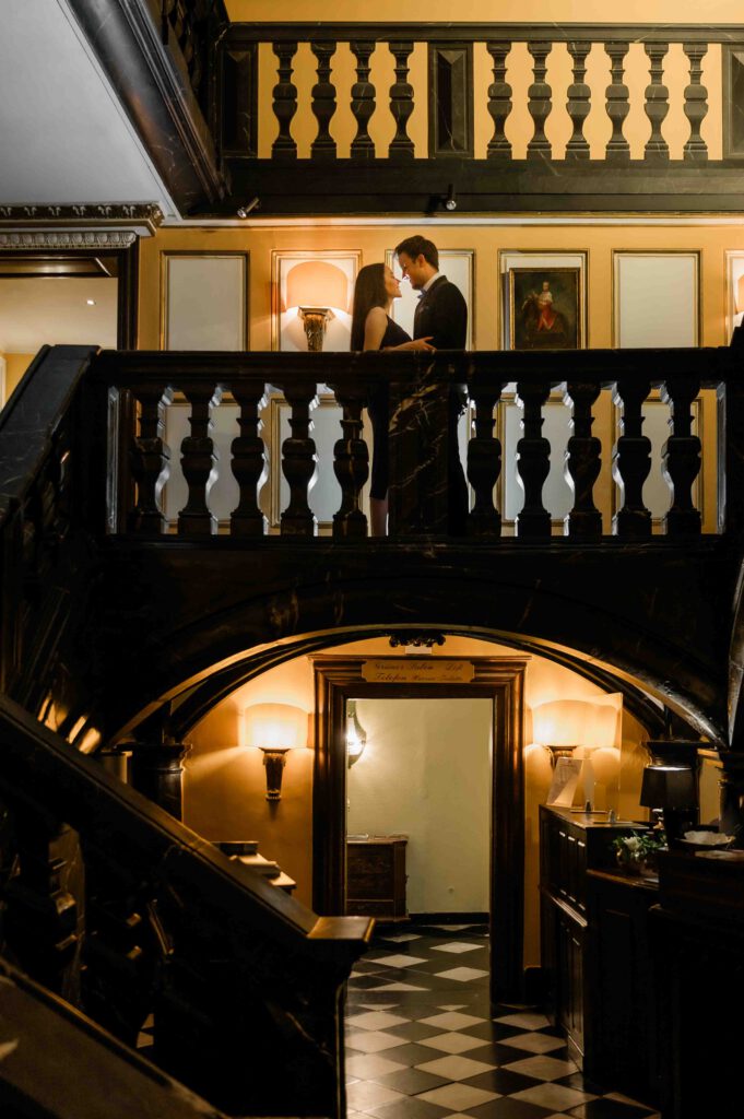 junges Paar steht im Treppenhaus vom Schloßhotel Hugenpoet