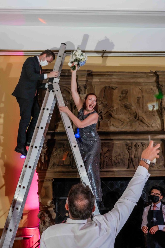 Eine Frau steht auf der Leiter und freut sich über den Brautstrauß