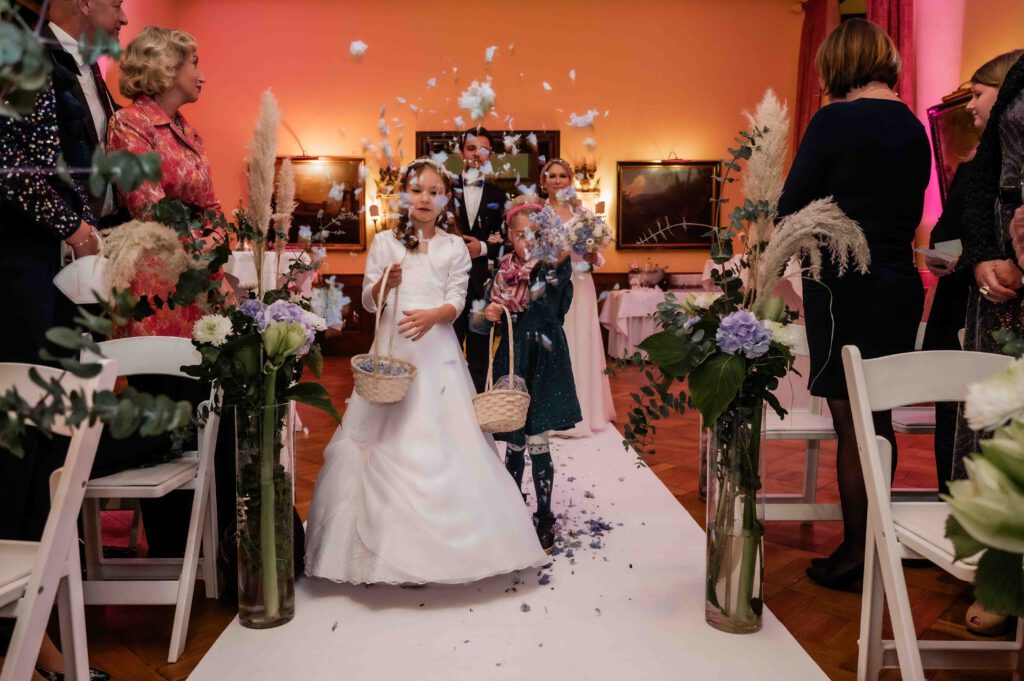 Blumenkinder werfen Blumen beim Einzug zu Hochzeit