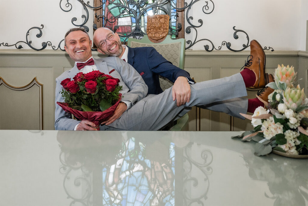 hochzeitsfotograf essen fotografiert gleichgeschlechtliches Brautpaar im Standesamt auf einem Stuhl
