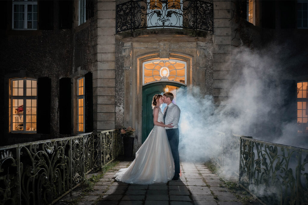 hochzeitsfotograf solingen fotografiert ein brautpaar am eingang vom wasserschloss hackhausen im nebel