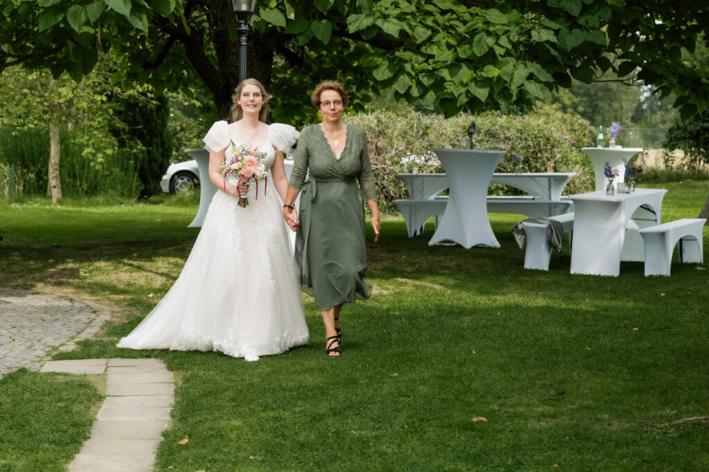 Braut wird von ihrer Mutter zur Trauung geführt