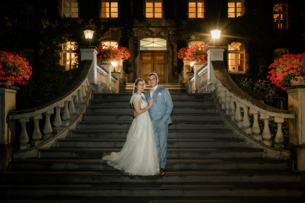 Brautpaar steht nachts auf der Treppe von schloss linnep