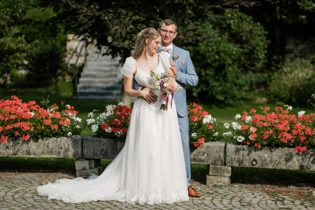 Brautpaar steht vor einem Blumenbeet