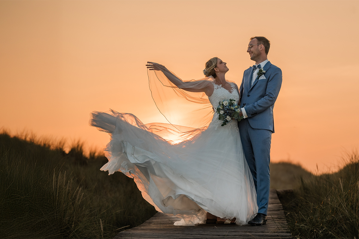 hochzeitsfotograf essen fotografiert ein glückliches Brautpaar in den Dünen im Sonnenuntergang