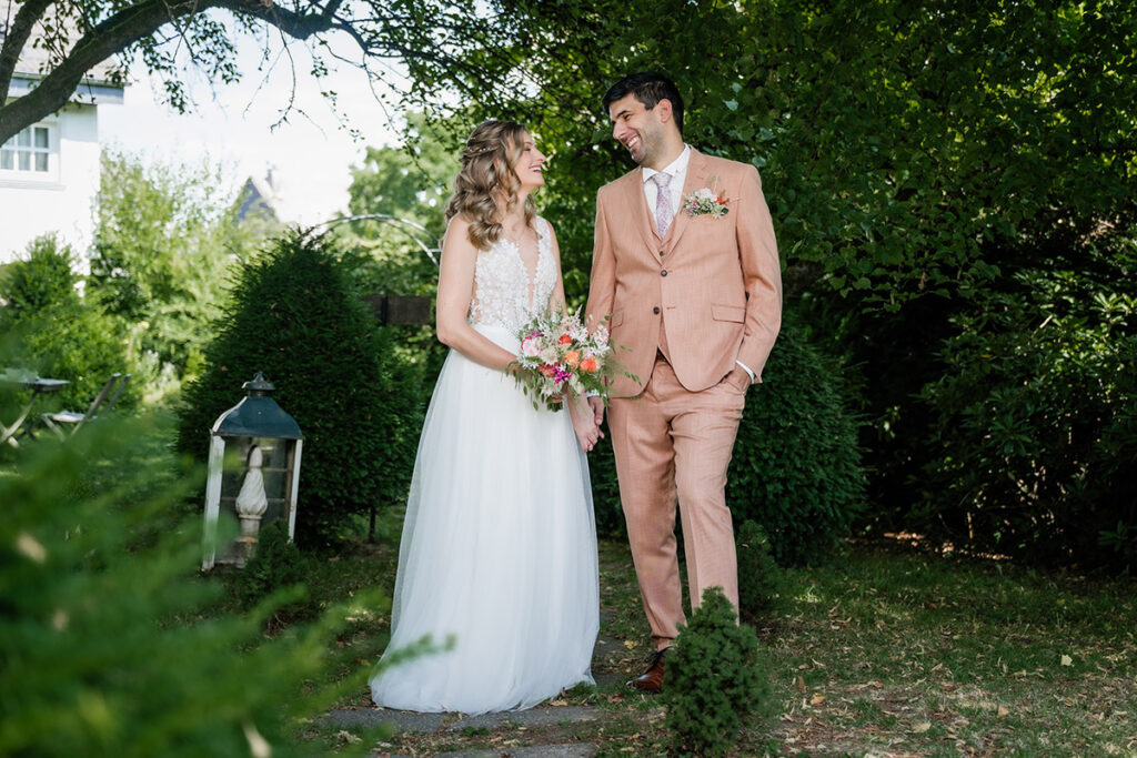 Brautpaarshooting im Garten des Romantik Hotel Neuhaus Iserlohn, Bräutigam hebt lachende Braut hoch, Hochzeitsfotografie Andreas Zabel