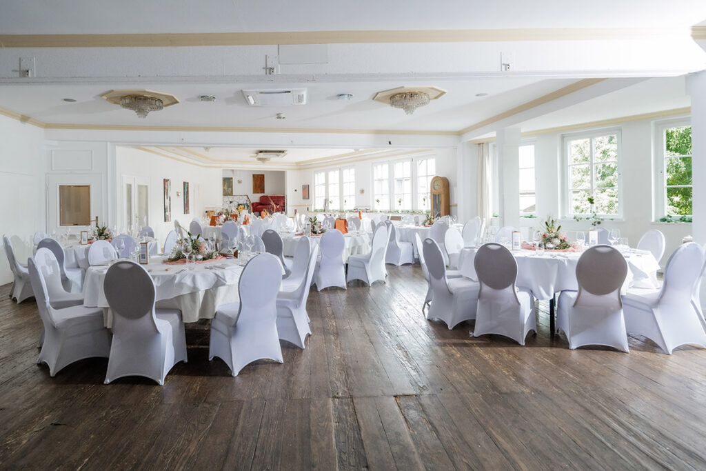 Elegante Tischdekoration für eine Hochzeit im Romantik Hotel Neuhaus Iserlohn, festlich gedeckte runde Tische mit Blumengestecken in Rosa und Weiß