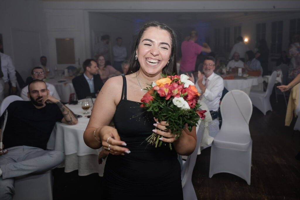 Strahlende Braut mit Brautstrauß auf der Tanzfläche während der Hochzeitsfeier im Romantik Hotel Neuhaus Iserlohn, Hochzeitsfotografie Andreas Zabel