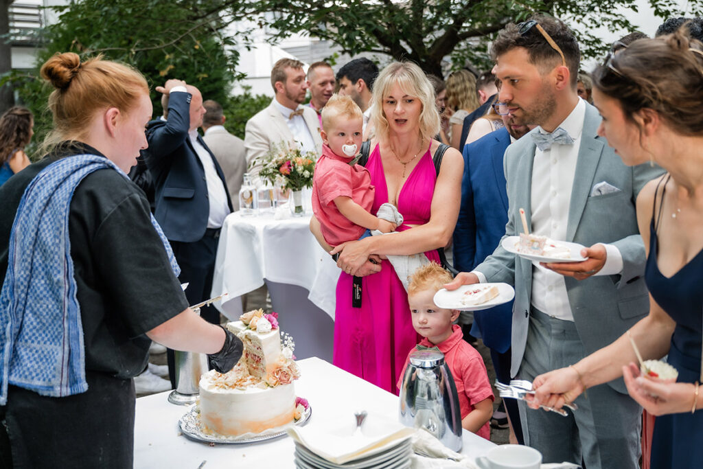 Hochzeitsgäste warten auf den Anschnitt der Hochzeitstorte im Außenbereich des Romantik Hotel Neuhaus in Iserlohn