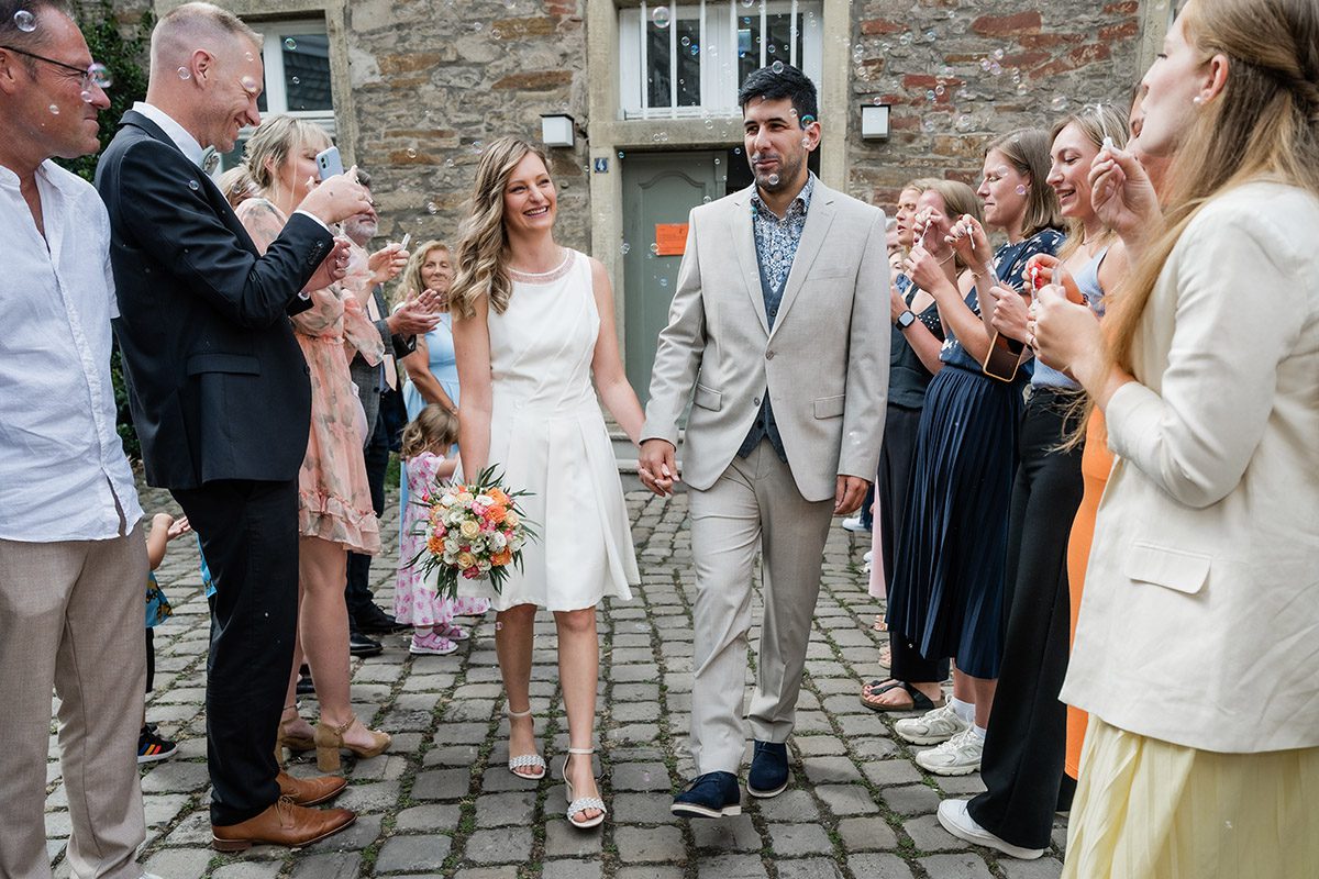 Brautpaar zieht nach der Trauung am Standesamt Herdecke durch ein Spalier aus Seifenblasen, fotografiert von Andreas Zabel Hochzeitsfotograf Herdecke