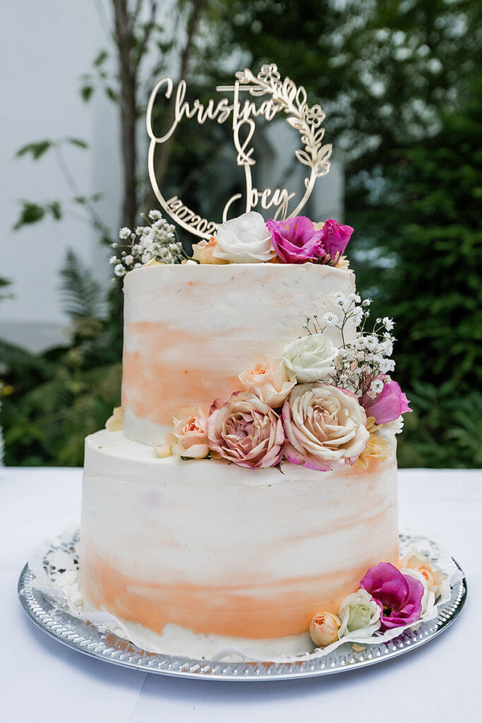 Zweistöckige Hochzeitstorte mit Pfirsich-Farbverlauf und echtem Blumenschmuck, fotografiert von Hochzeitsfotograf Andreas Zabel