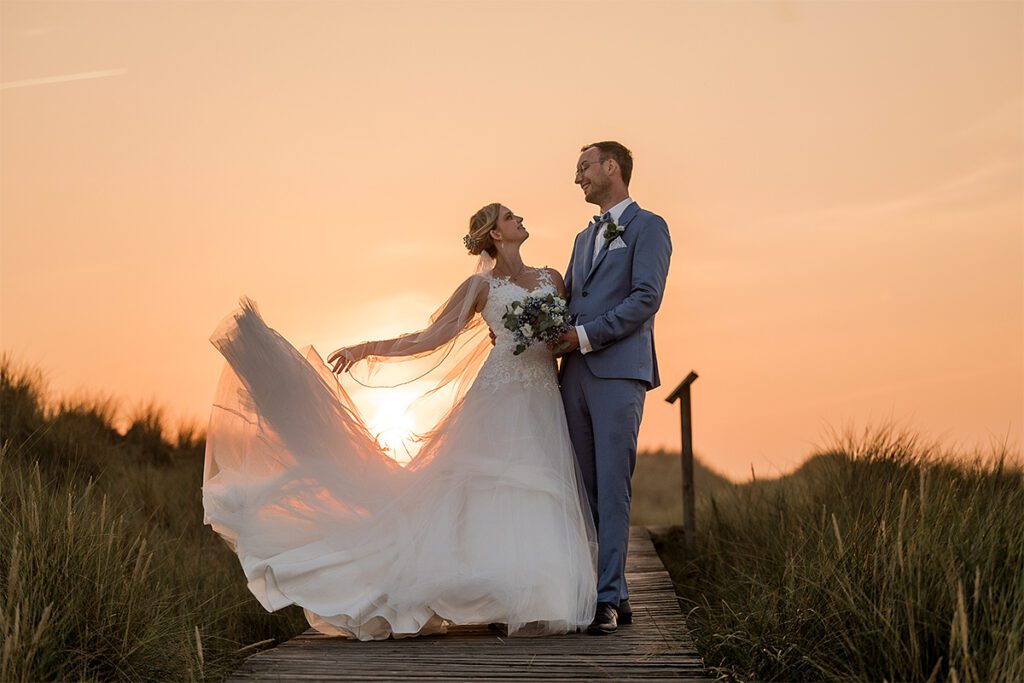 Hochzeitsfotograf in Essen fotografiert Brautpaar mit Hochzeitsstrauß während der Golden Hour im Sonnenuntergang