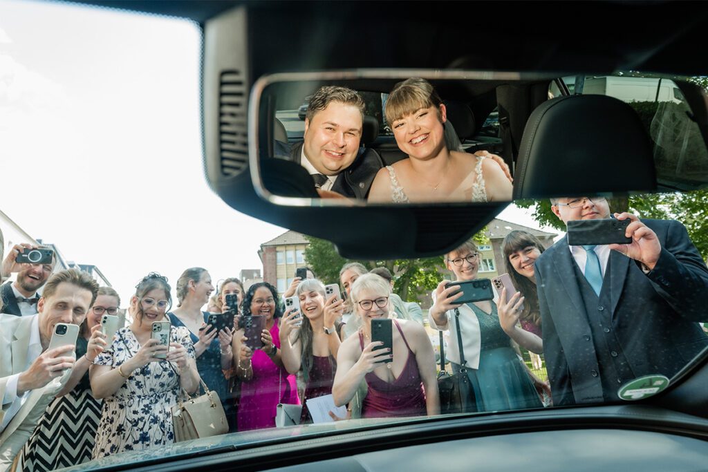 Hochzeitsgäste Fotografieren das Brautpaar im Auto