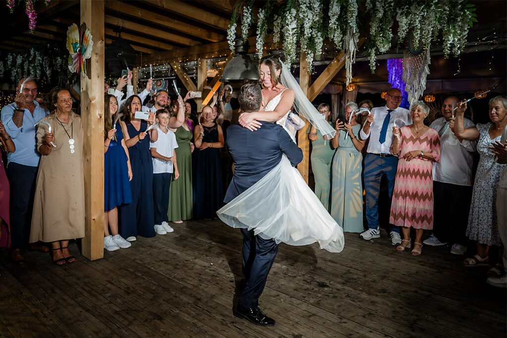 Schwungvoller Hochzeitstanz in Essen: Bräutigam wirbelt die Braut auf der Holz-Tanzfläche vor den feiernden Gästen herum