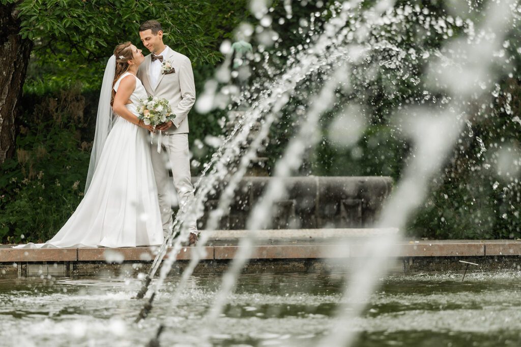 Brautpaar beim Hochzeits-Shooting am Brunnen in Essen, fotografiert durch spritzendes Wasser