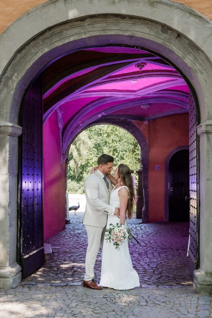 Romantisches Brautpaar-Porträt in einem historischen Torgang mit farbigem Lichtakzent bei einer Hochzeit in Essen
